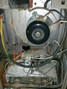 Damaged furnace with rust and corroded wiring, indicating need for professional heating system repair.